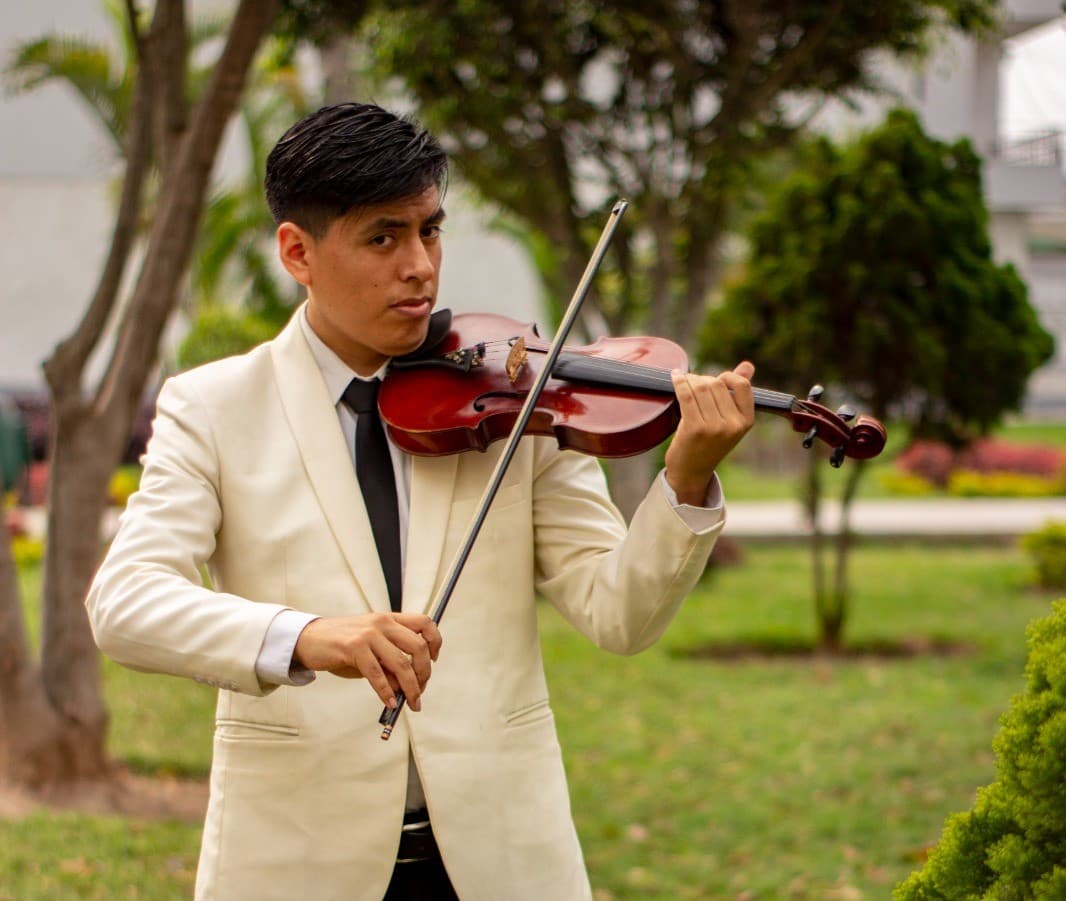 Pedro Olivos ejecutando violin en parque con flores